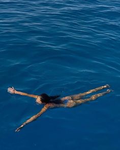 a woman floating in the water with her arms outstretched