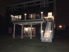 an apartment building with stairs and lights on the front lawn at night, lit up by outdoor lighting