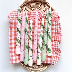 six candles are sitting in a basket on a tablecloth with pine branches and holly decorations