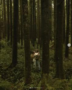 two people standing in the middle of a forest