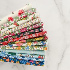 a stack of colorful fabric on top of a marble countertop with flowers and leaves