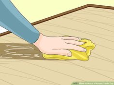 a person wiping down the floor with a yellow cloth on top of it and a hand that is holding a sponge