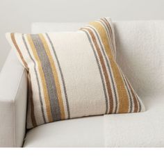 a white couch with a striped pillow sitting on it's back end and side