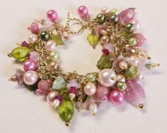 Make a statement with this one-of-a-kind floral charm bracelet. Gold wire wrapped freshwater pearls, glass pearls, cut Swarovski crystals, Czech glass flowers and leaves, gold plated findings, and assorted glass beads are hung on a gold-plated chain and finished with a matching toggle clasp.  This bright and colorful beaded bracelet comes with all charms shown. Bracelet length can be adjusted as requested, prior to checkout, by selecting a size. Makes a great addition to your collection or a won Elegant Beaded Dangle Charm Bracelet, Whimsical Handmade Pearl Jewelry, Pink Charms Jewelry For Wedding, Pearl Jewelry With Round Bead Charms, Elegant Pink Wire Wrapped Bracelets, Whimsical Pink Bracelet Jewelry, Whimsical Pearl Beaded Jewelry, Whimsical Beaded Pearl Jewelry, Elegant Pink Dangle Charm Bracelet