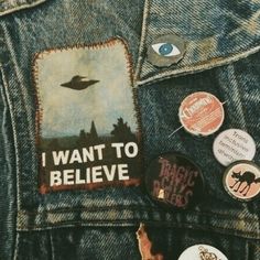 buttons and badges are on the back of a jean jacket that says i want to believe