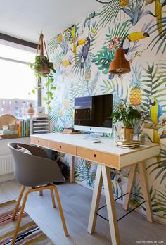 a desk with a computer on top of it in front of a wallpapered wall