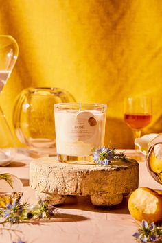 a candle sitting on top of a piece of wood next to some wine glasses and lemons