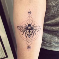 a tattoo with a bee on it's arm and an ornamental design in the middle