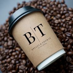 a coffee cup sitting on top of a pile of coffee beans with the letter b t