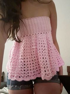 a woman in short shorts is wearing a pink crochet top and has her back turned to the camera