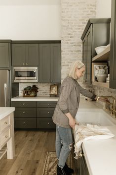 a woman standing in a kitchen next to a sink