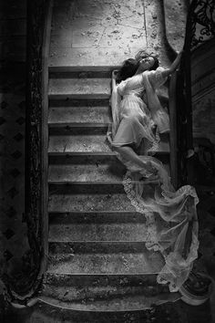 black and white photo of woman in dress on stairs