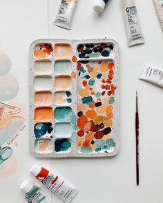 an artist's palette with paint and watercolors