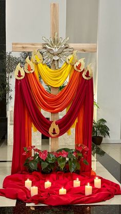 an altar decorated with red, orange and yellow drapes and candles in front of it