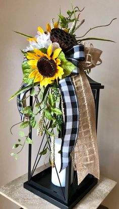 a vase with sunflowers and greenery in it on top of a table