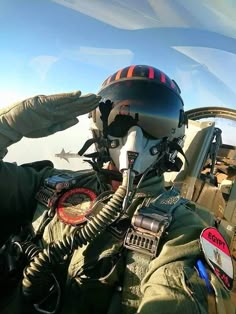 an air force pilot wearing a helmet and goggles sitting in the cockpit of a plane