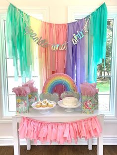 a rainbow themed birthday party with cake and cupcakes