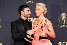 a man and woman holding two awards in their hands on the red carpet at an event