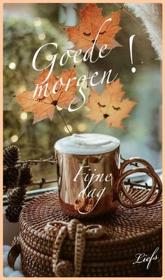 a coffee cup sitting on top of a wicker basket next to an autumn tree