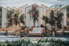 an outdoor wedding set up with flowers and greenery on the walls, couches and chairs