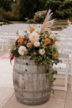 a wooden barrel with flowers and greenery on the side for an outdoor wedding ceremony