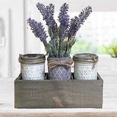 three jars with lavender flowers in them are sitting on a wooden tray that holds mason jars