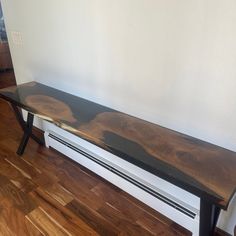 a wooden bench sitting on top of a hard wood floor next to a white wall