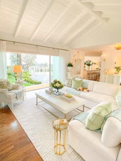 a living room filled with white furniture and lots of green pillows on top of it