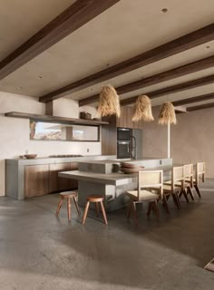 a modern kitchen with an island counter and chairs in the center, surrounded by wood beams