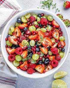 a white bowl filled with berries and limes