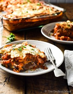 a white plate topped with lasagna next to a fork and glass of water