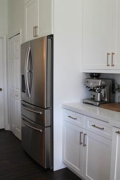 a metallic refrigerator freezer sitting inside of a kitchen next to white cabinets and drawers