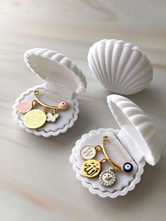 three different types of jewelry are sitting on a white table next to seashells