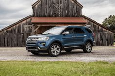 a blue ford explorer parked in front of a barn