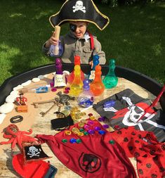 a little boy wearing a pirate hat sitting at a table with bottles and other items