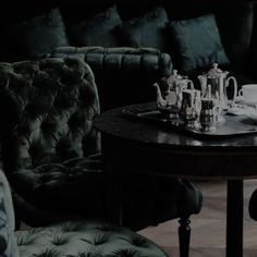 a dining room table and chairs with tea set on it in front of a couch