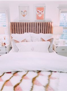 a white bed topped with pillows and blankets next to two framed pictures on the wall