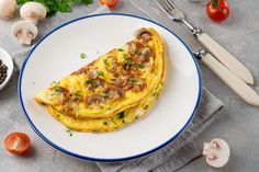 an omelet on a plate with mushrooms, tomatoes and parsley next to it