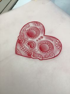 a red sugar skull tattoo on the back of a woman's shoulder and chest