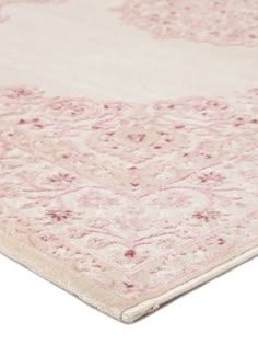 a pink and white area rug with an intricate design on the bottom, in front of a white background