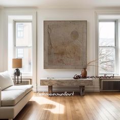 a living room with wood floors and white furniture in front of two large windows on the wall