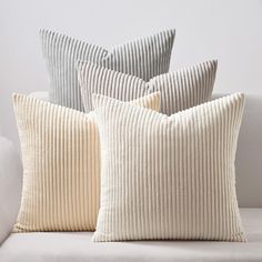 four pillows sitting on top of a white couch