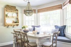 a dining room table with four chairs and a bench in front of the window,