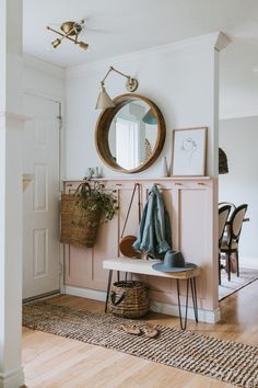 a room with a mirror, coat rack, and table in front of the door