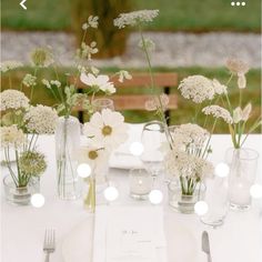 the table is set with white flowers in vases and silverware, along with an empty menu