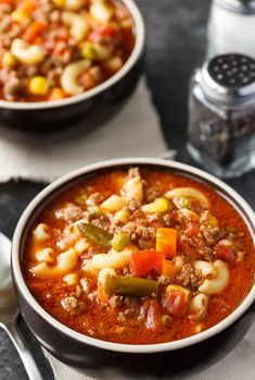 two bowls filled with soup on top of a table next to crackers and bread