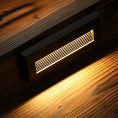 a light shines on the wood floor in front of a wall mounted heater