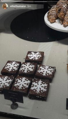 chocolate brownies and cookies are on display in a store window with snowflakes