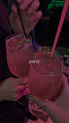 two people holding up pink drinks in their hands