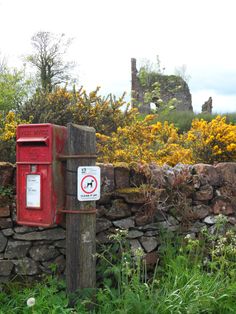 a red mailbox sitting next to a stone wall